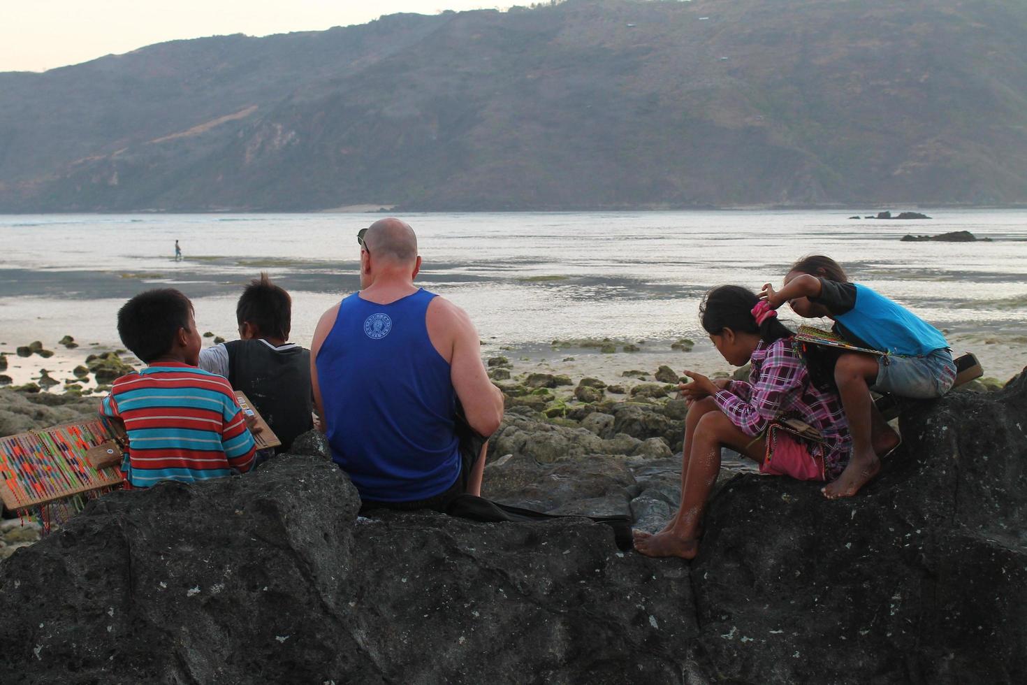 Lombok, Indonesia - August, 2014. tourists and local children playing together on the beach photo