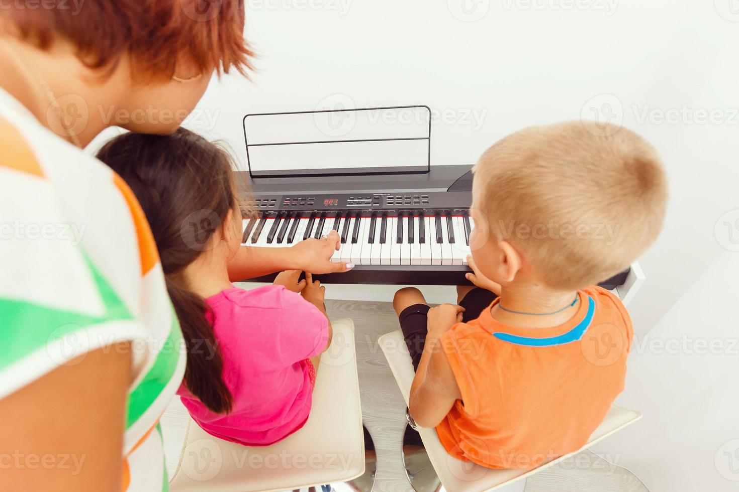 Mother teaching daughter to play piano photo