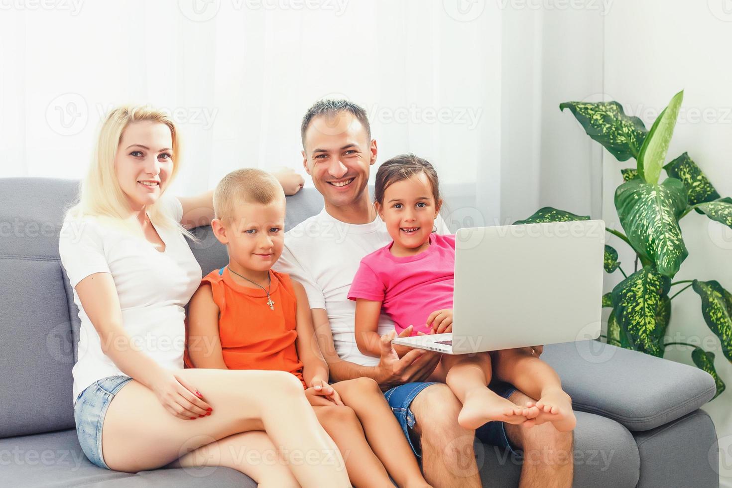 retrato de un alegre familia utilizando un ordenador portátil sentado en sofá a hogar foto