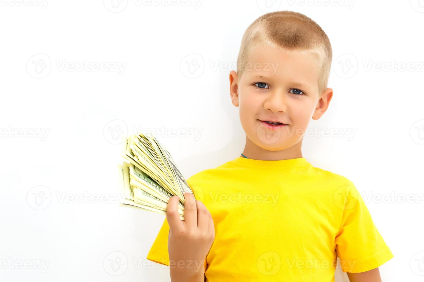 Portrait of a cheerful little boy holding a dollars over white background photo