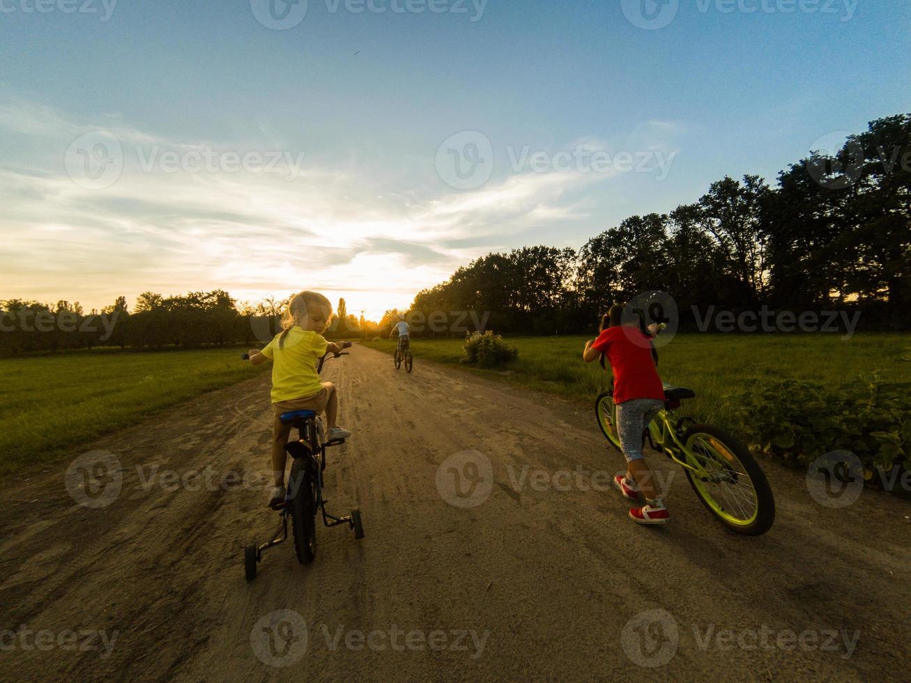 Three child riding a bicycle. The kids in a helmet riding a bike in the park. Beautiful kids. photo