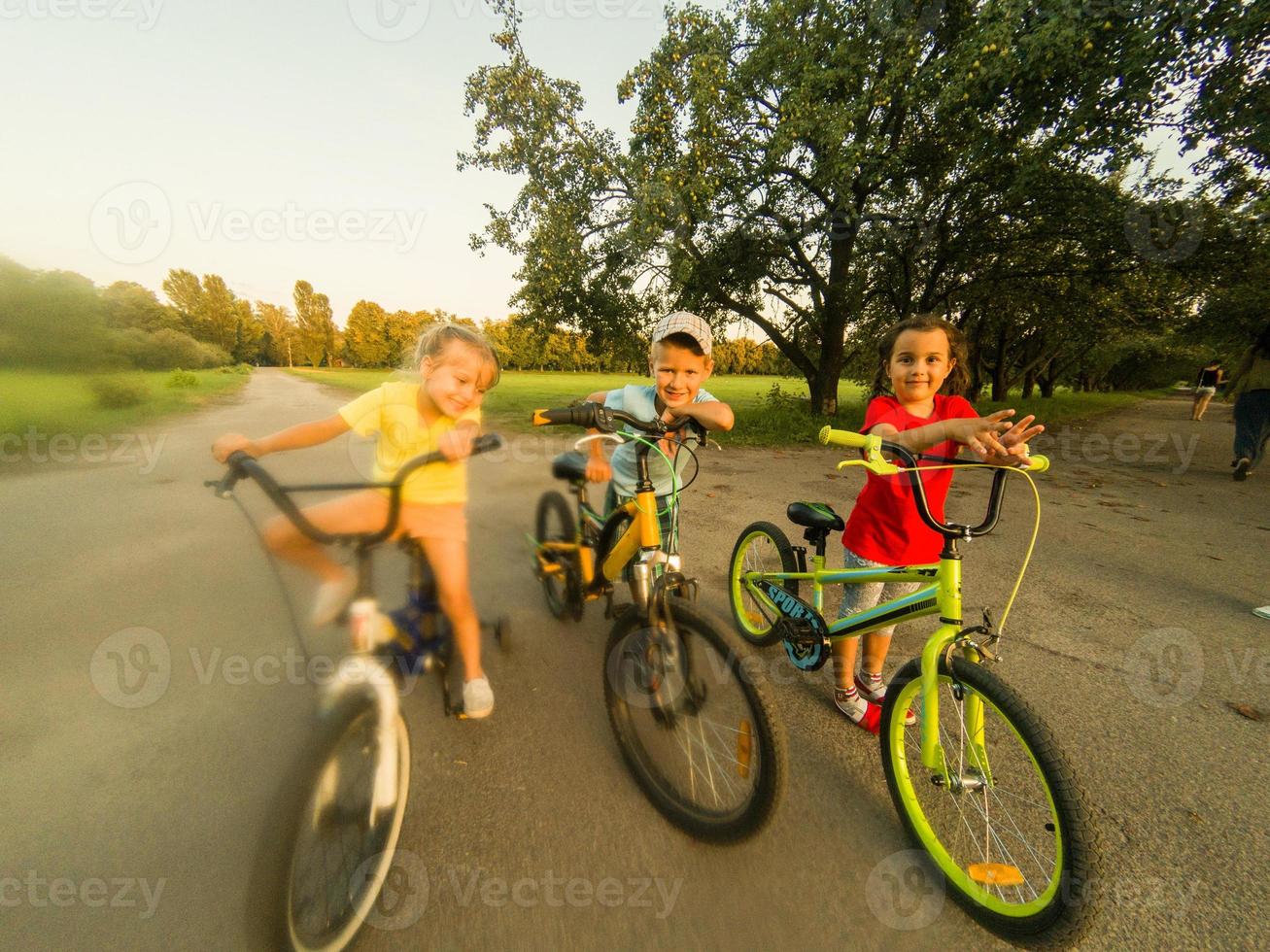 niños en bicicletas en el parque cerca escuela. foto