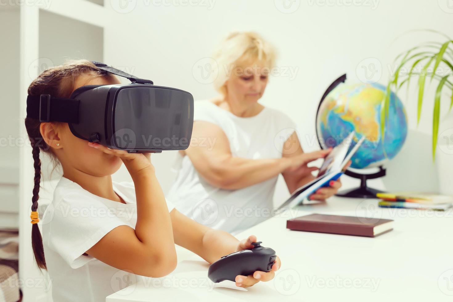 A young girl explains to an elderly woman how to use virtual reality glasses. The older generation and new technologies. photo