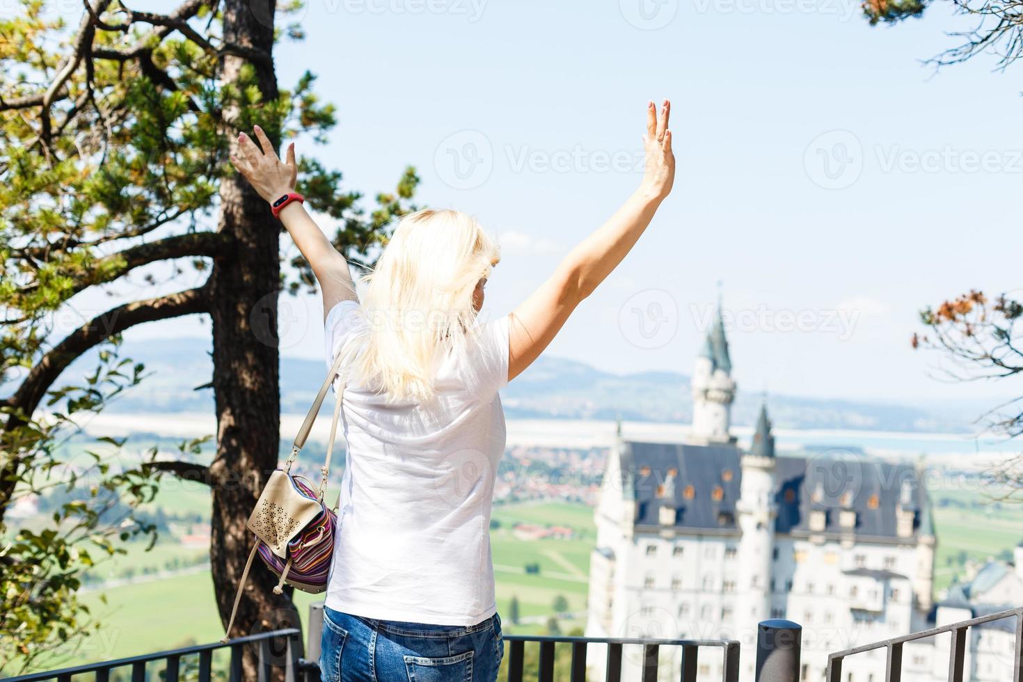 Young woman with famous royal castle Neuschwanstein on background. Happy winter weekend in the countryside. Vacation in mountains. Alps, Bavaria, Germany photo