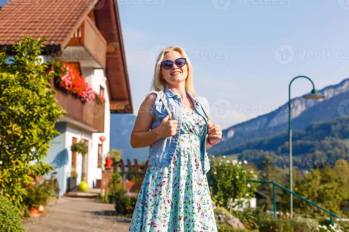 joven mujer es en pie por de madera casas pueblo en montañas. viajar, estilo de vida concepto. Alpes, Europa. foto