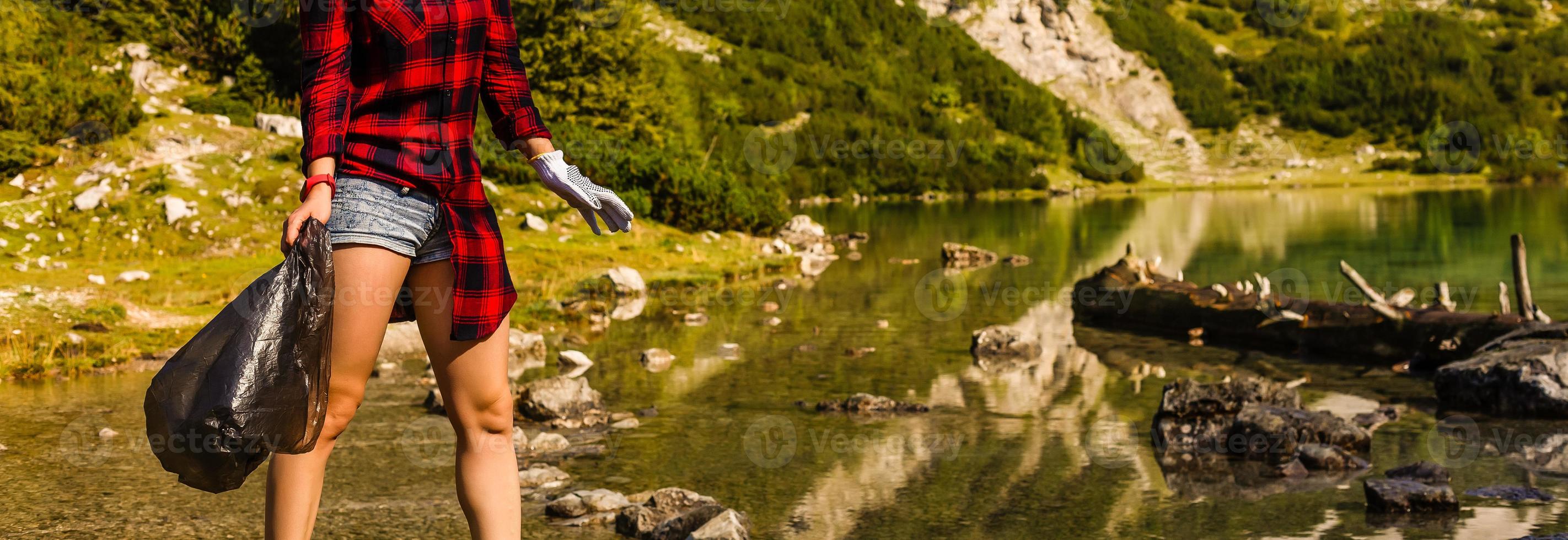 Woman hand collecting garbage of the grass in the mountain with copy space photo