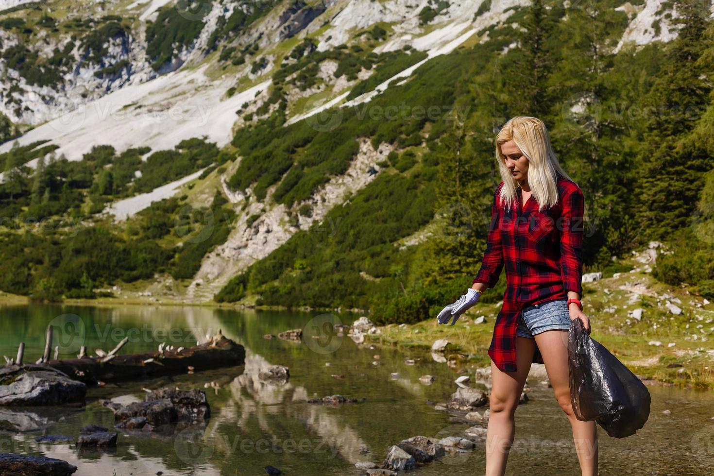 Woman hand collecting garbage of the grass in the mountain with copy space photo