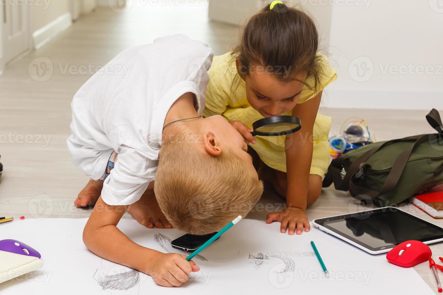 Children boy and girl drawing playing with magnifying glass photo