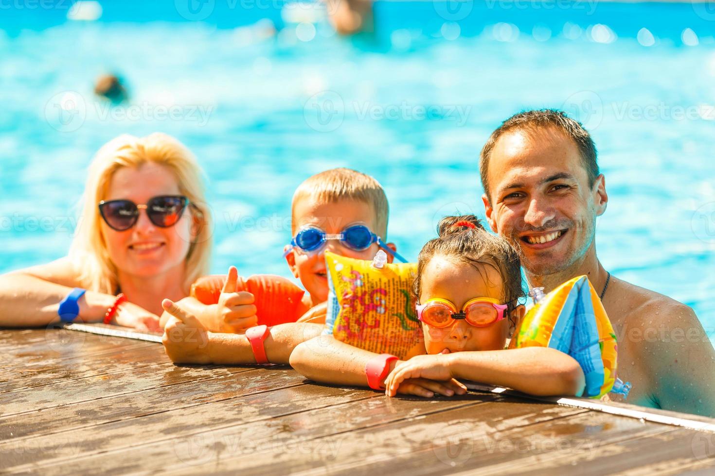 Family in swimming pool, man woman boy girl staying in pool at the deck