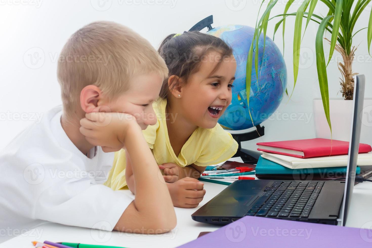 Portrait of smart schoolgirls and schoolboys looking at the laptop in classroom photo