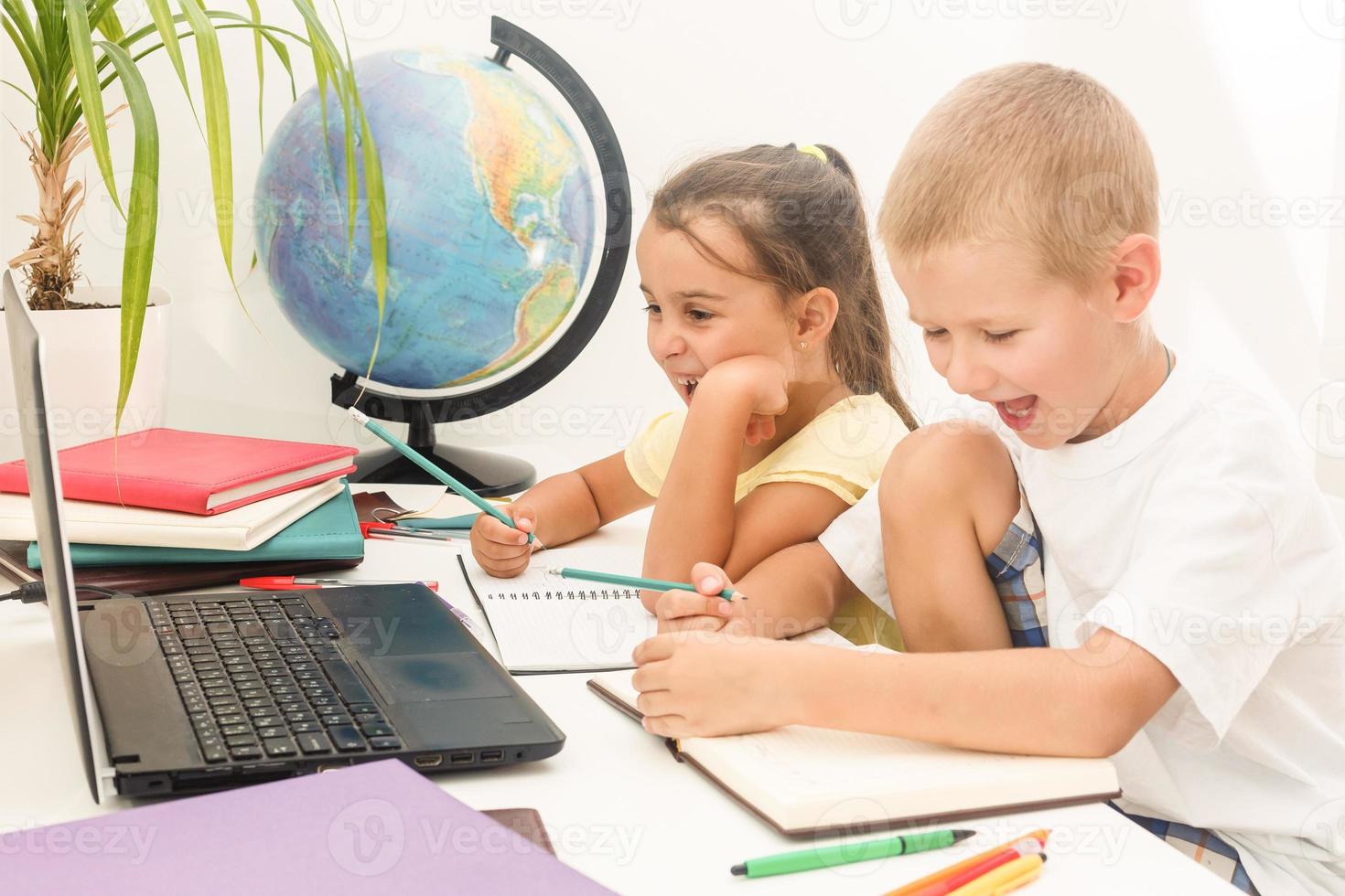 Portrait of two schoolchildren sitting by one desk during drawing lesson while boy looking at his mates copybook photo
