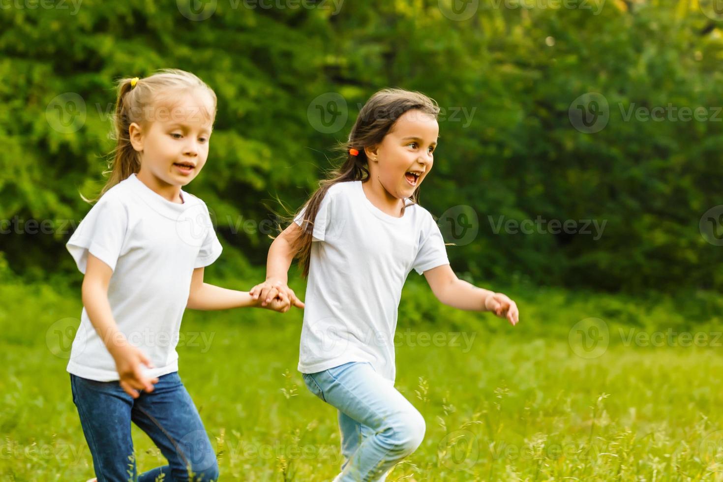 Two little sisters run on the road in park on a sunny summer day. Family time. Cute babies. Soft focus photo