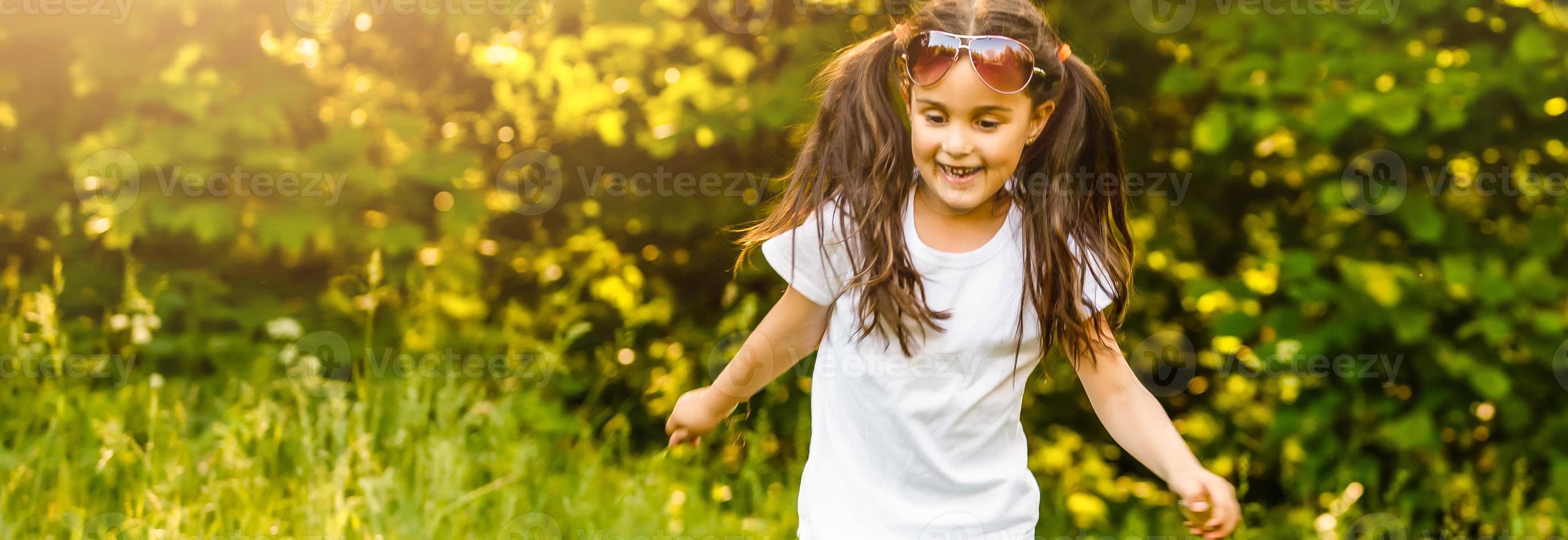 Little girl running on green grass. Beautiful warm summer evening. photo