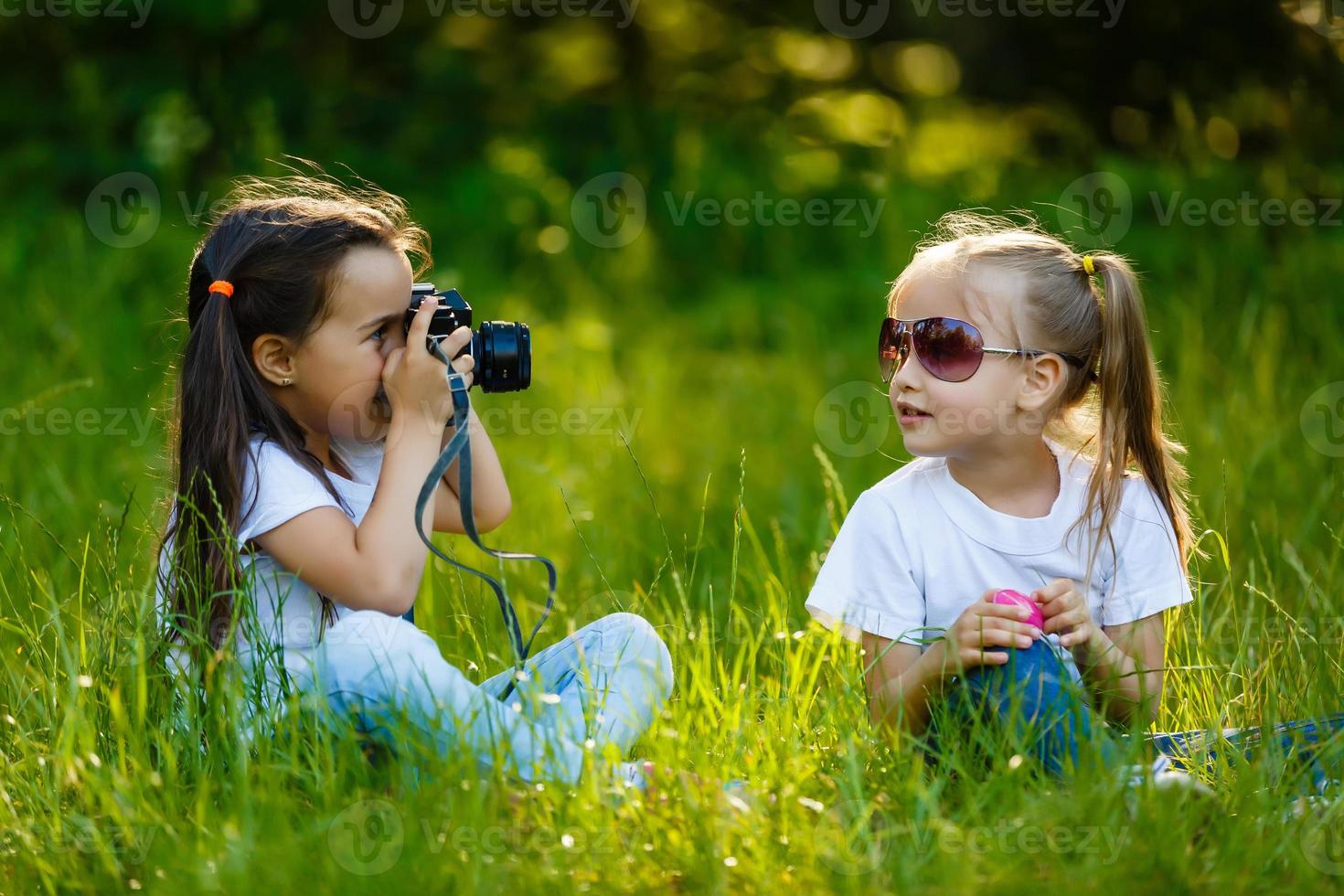 Two children girlhold a camera take a picture each other photo