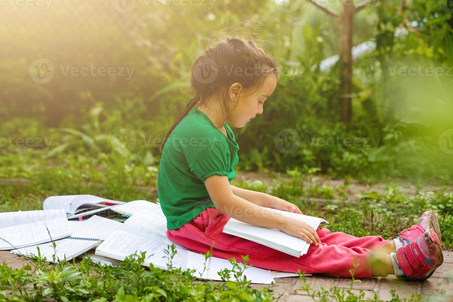 lille niña retrato con libros en jardín durante yo educación a hogar. distante remoto yo aprendiendo. moderno colegio familia estudiar. foto