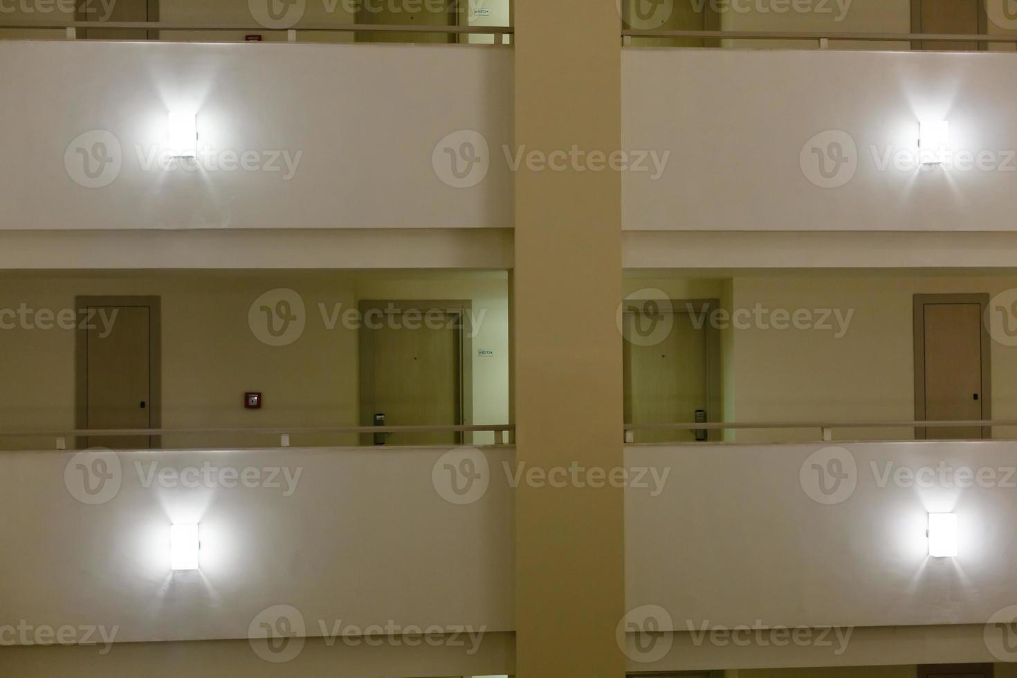 Spacious light hallway with many doors leading into hotel rooms. photo