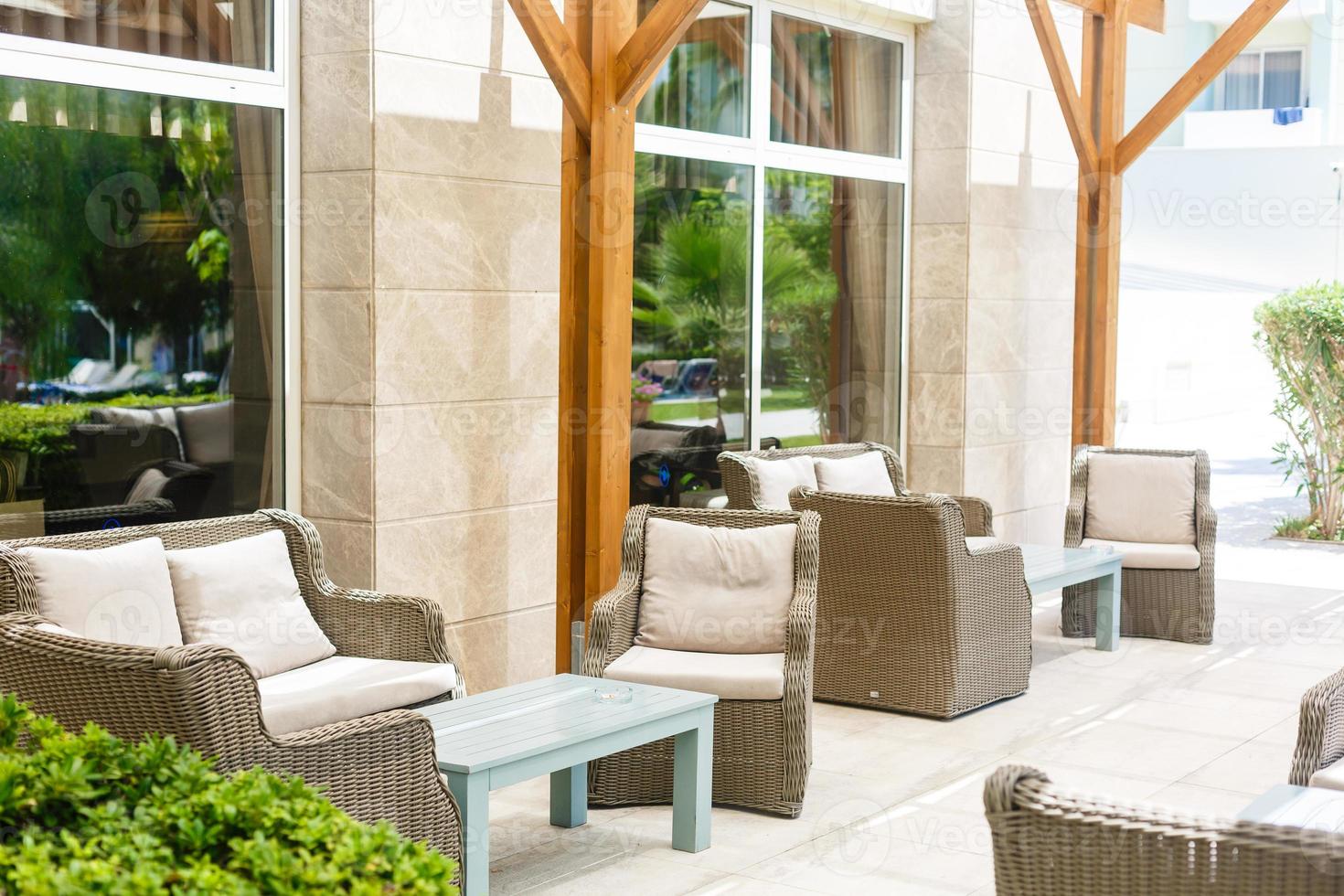 Lounge area for guests outside, rattan sofas and chairs around the table with flowers outside photo