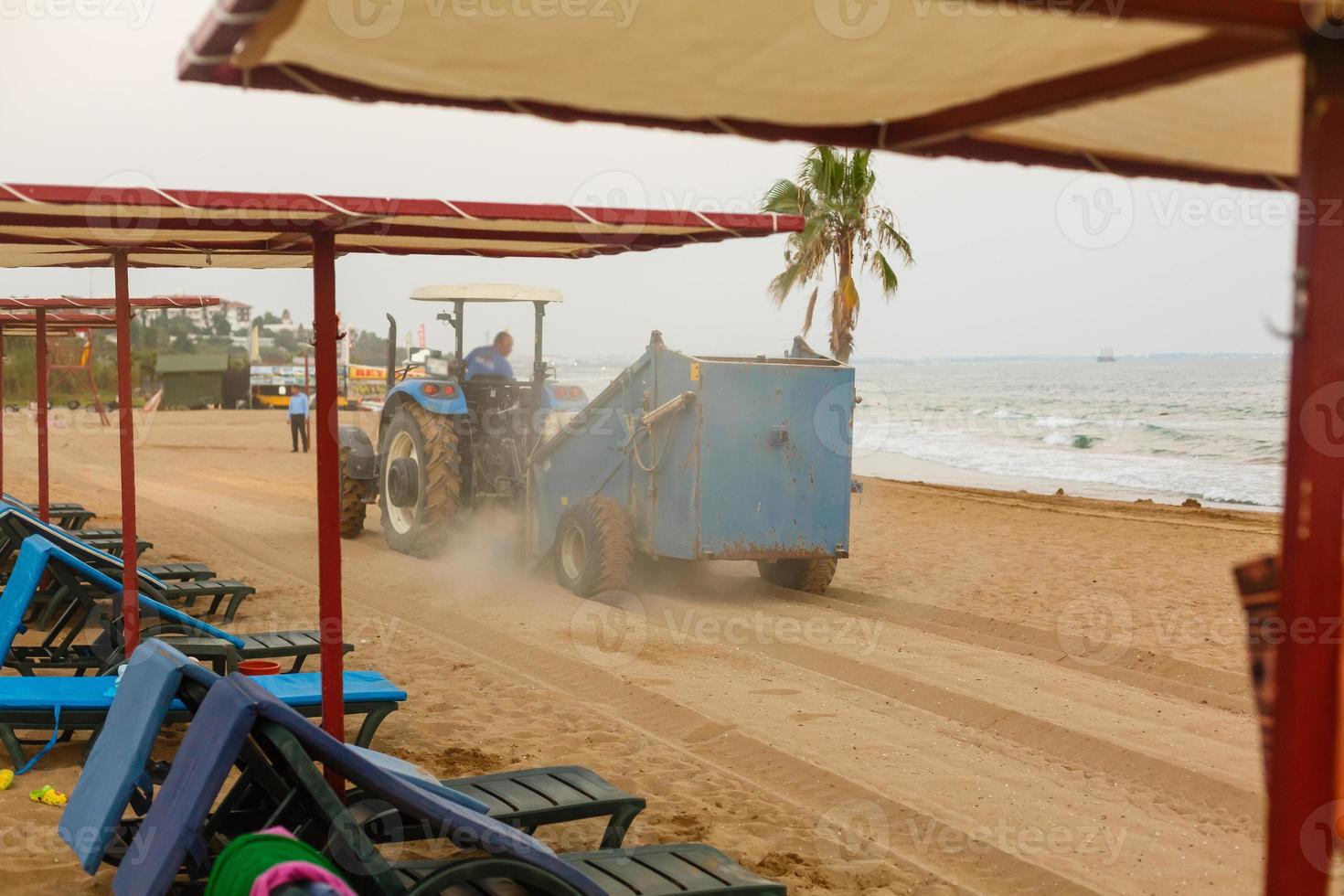 tractor con remolque limpiador limpieza arena en el playa foto