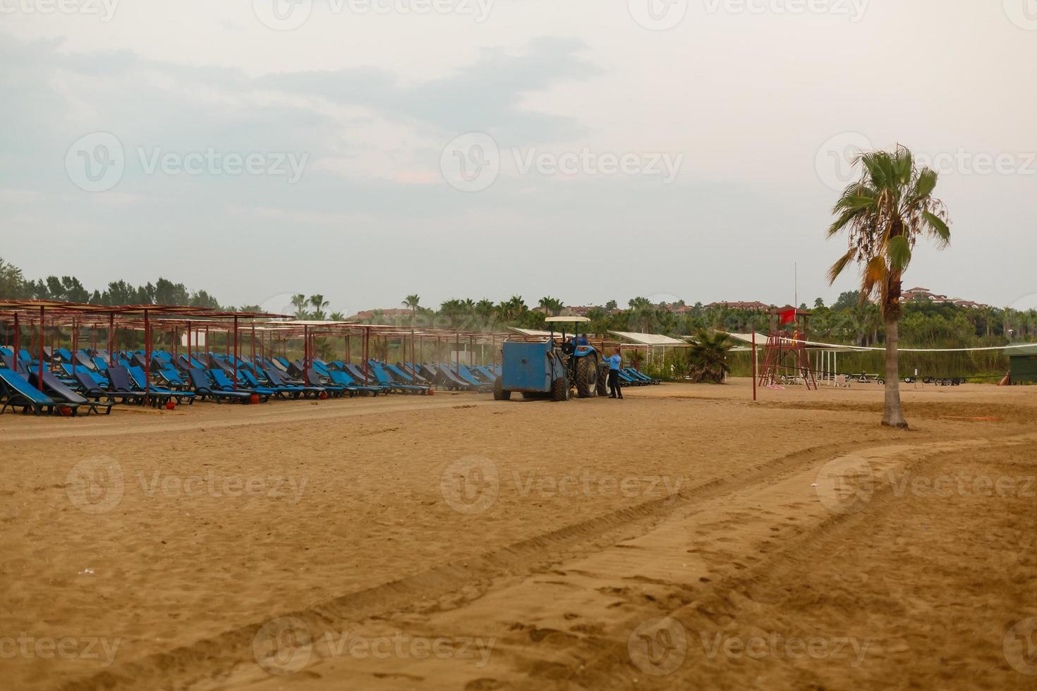 tractor con remolque limpiador limpieza arena en el playa foto