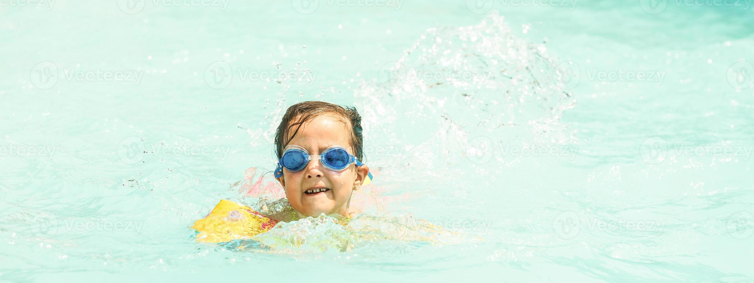 little girl is swimming in the pool. Summer holidays and vacation concept photo