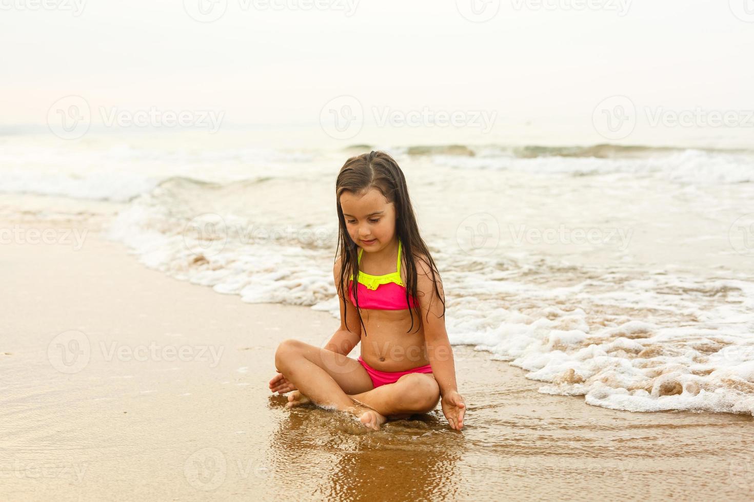 contento niña en un tropical playa Oceano tiene un divertido con chapoteo foto
