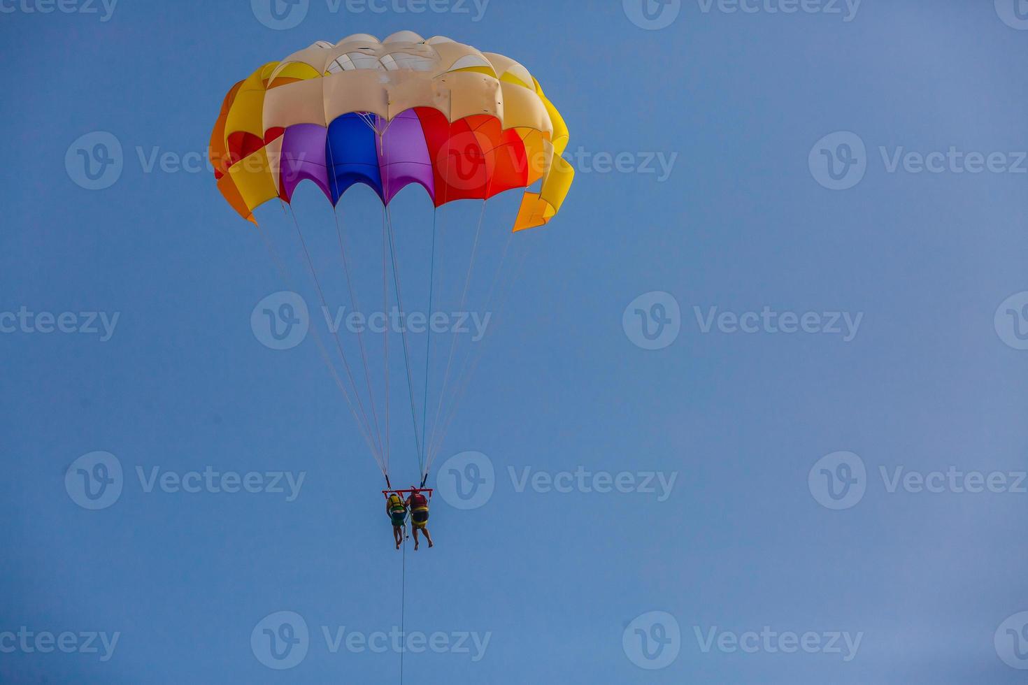 Spectacular scenic view on the sea and blue sky with people flying on a colorful parachute towed by a motor boat photo