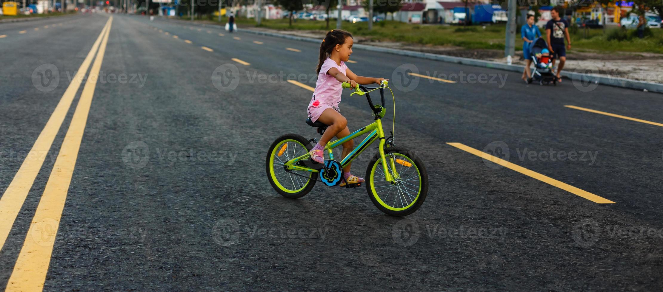 Children learning to drive a bicycle on a driveway outside. Little girls riding bikes on asphalt road in the city wearing helmets as protective gear. photo