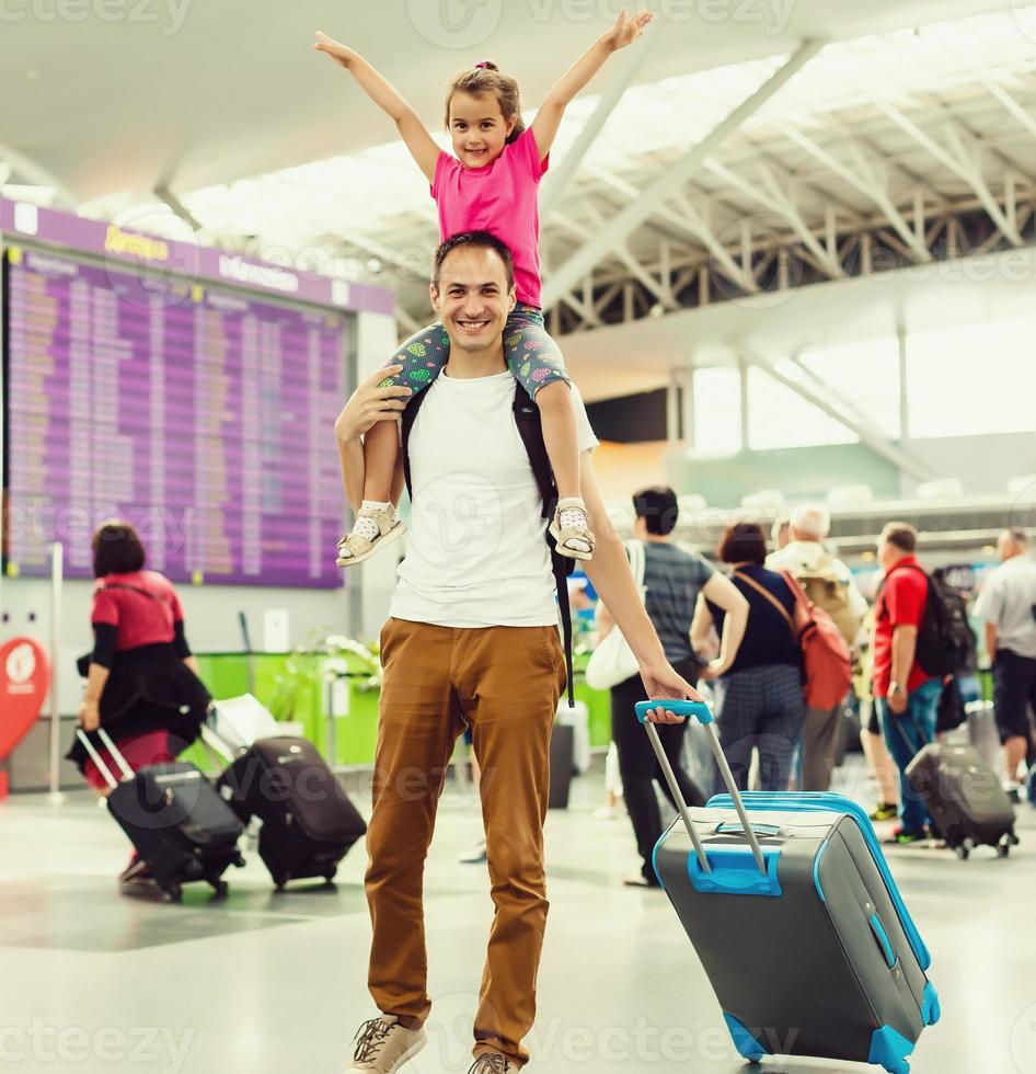 Happy little girl embracing her dad in airport lounge after arrival with mother photo