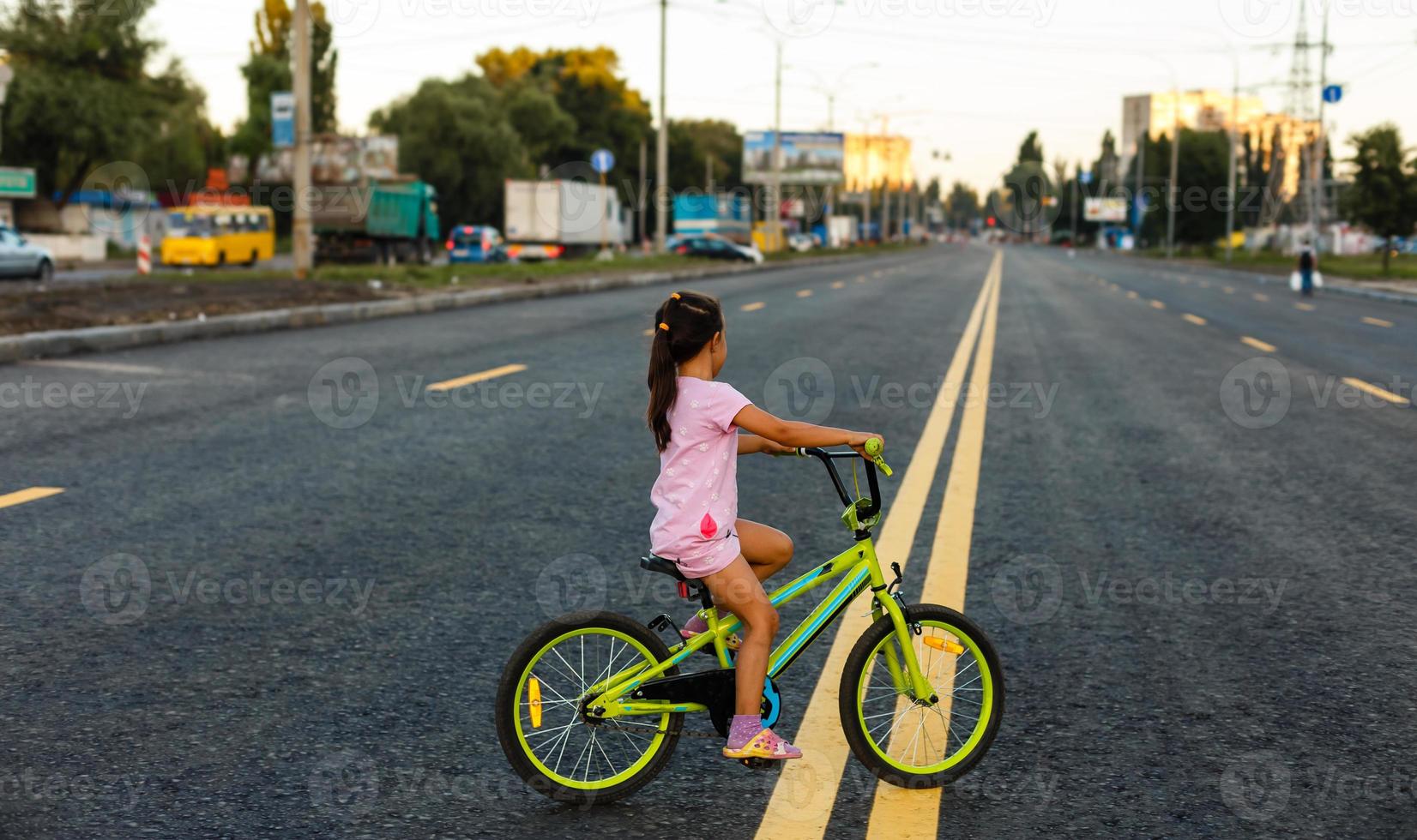 Children learning to drive a bicycle on a driveway outside. Little girls riding bikes on asphalt road in the city wearing helmets as protective gear. photo