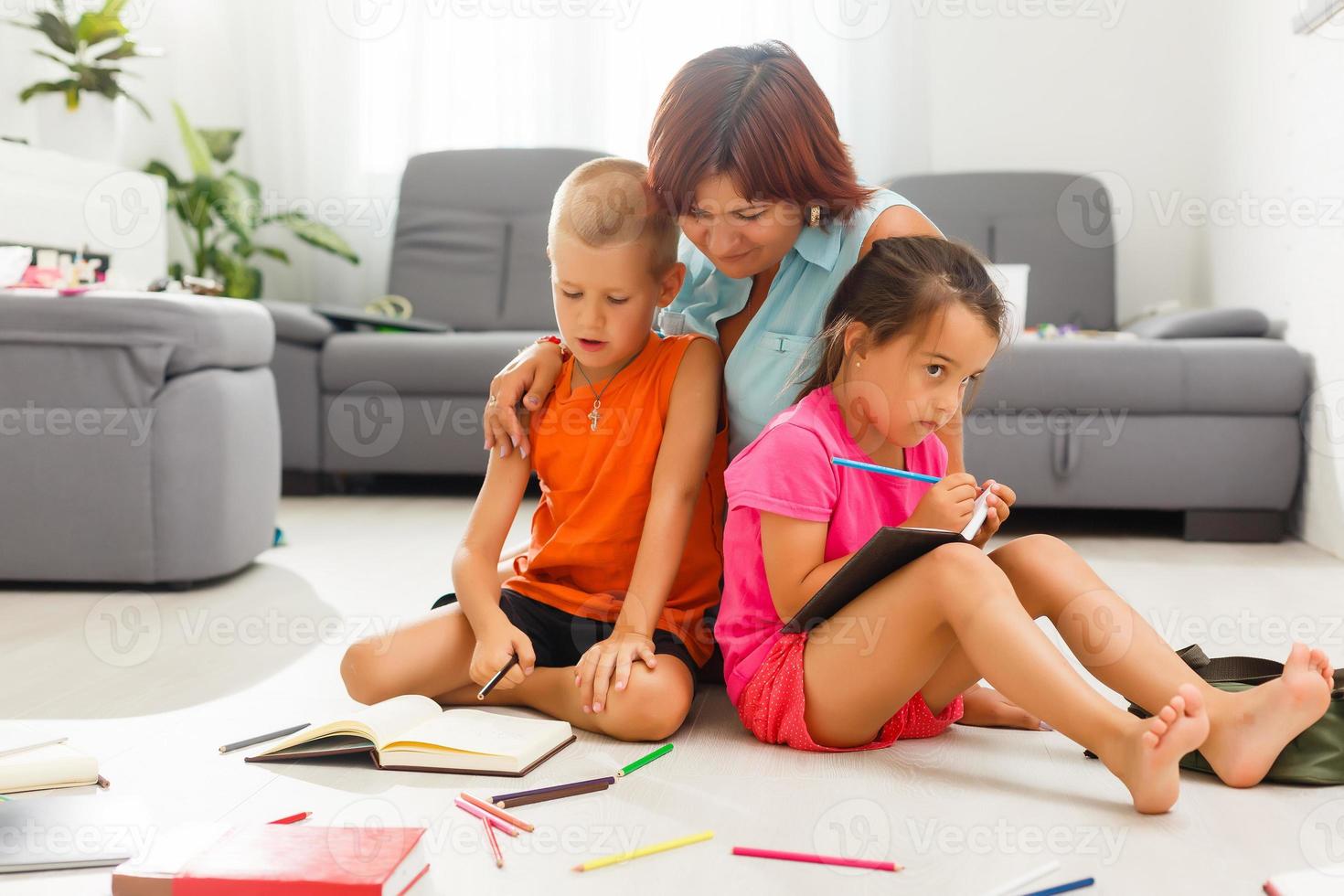 madre y niños haciendo deberes en el piso foto