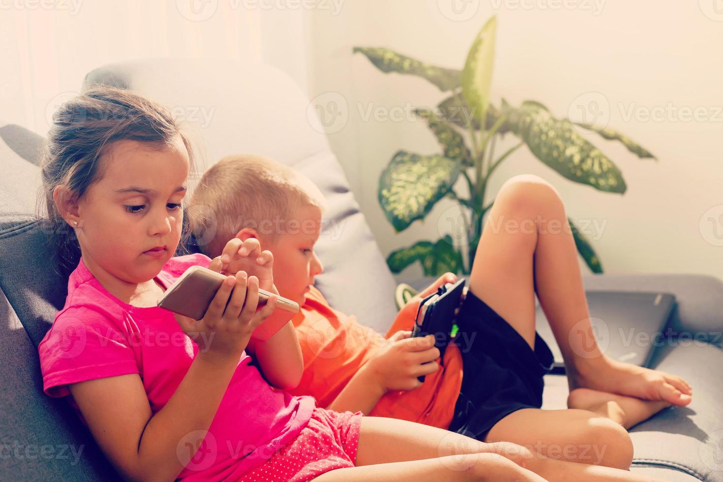 Two children addicted tablet. asian child watching tablet  kid use telephone together on their bed photo