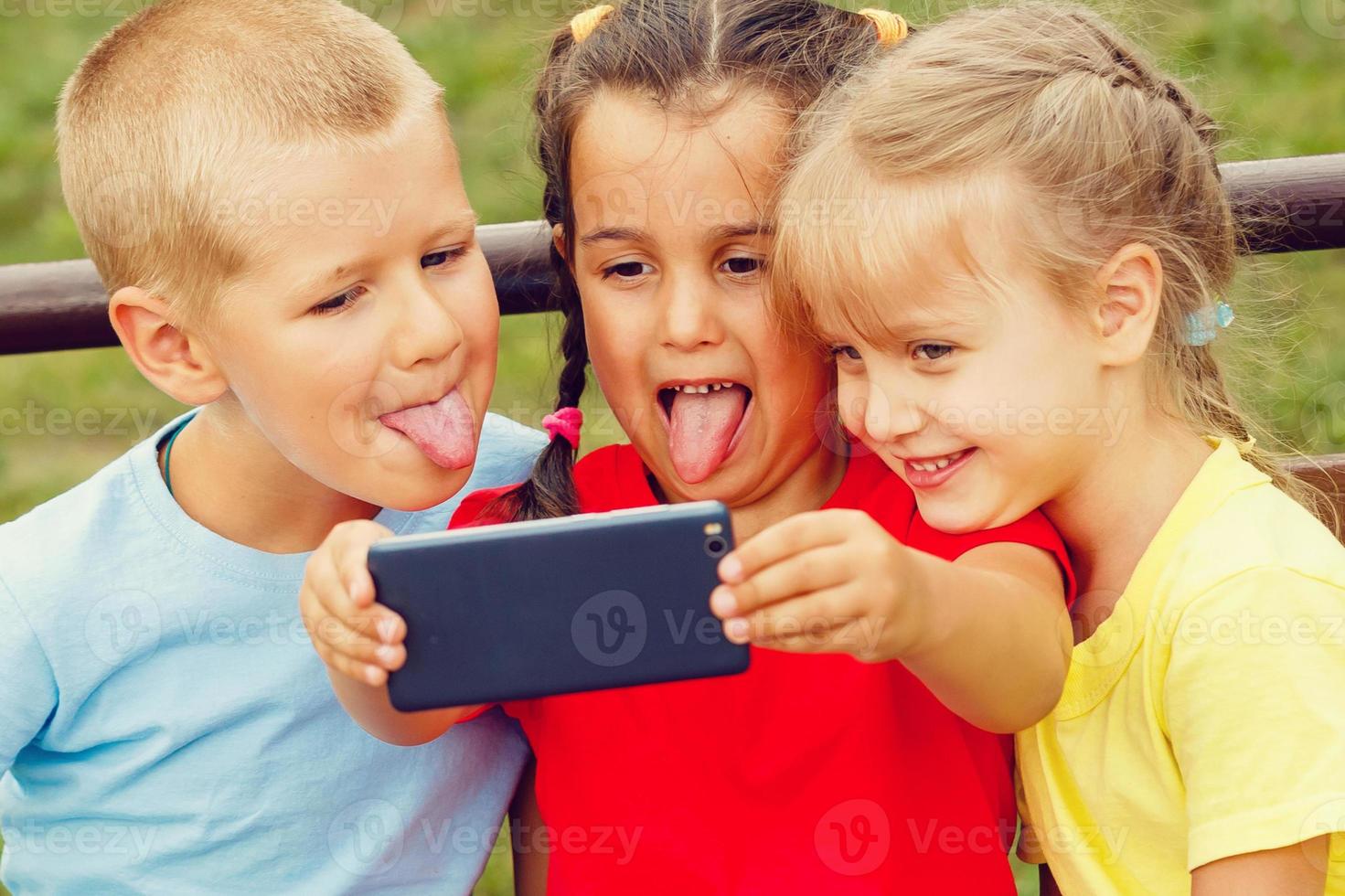 Group Of Children Sitting On Bench In Mall Taking Selfie photo