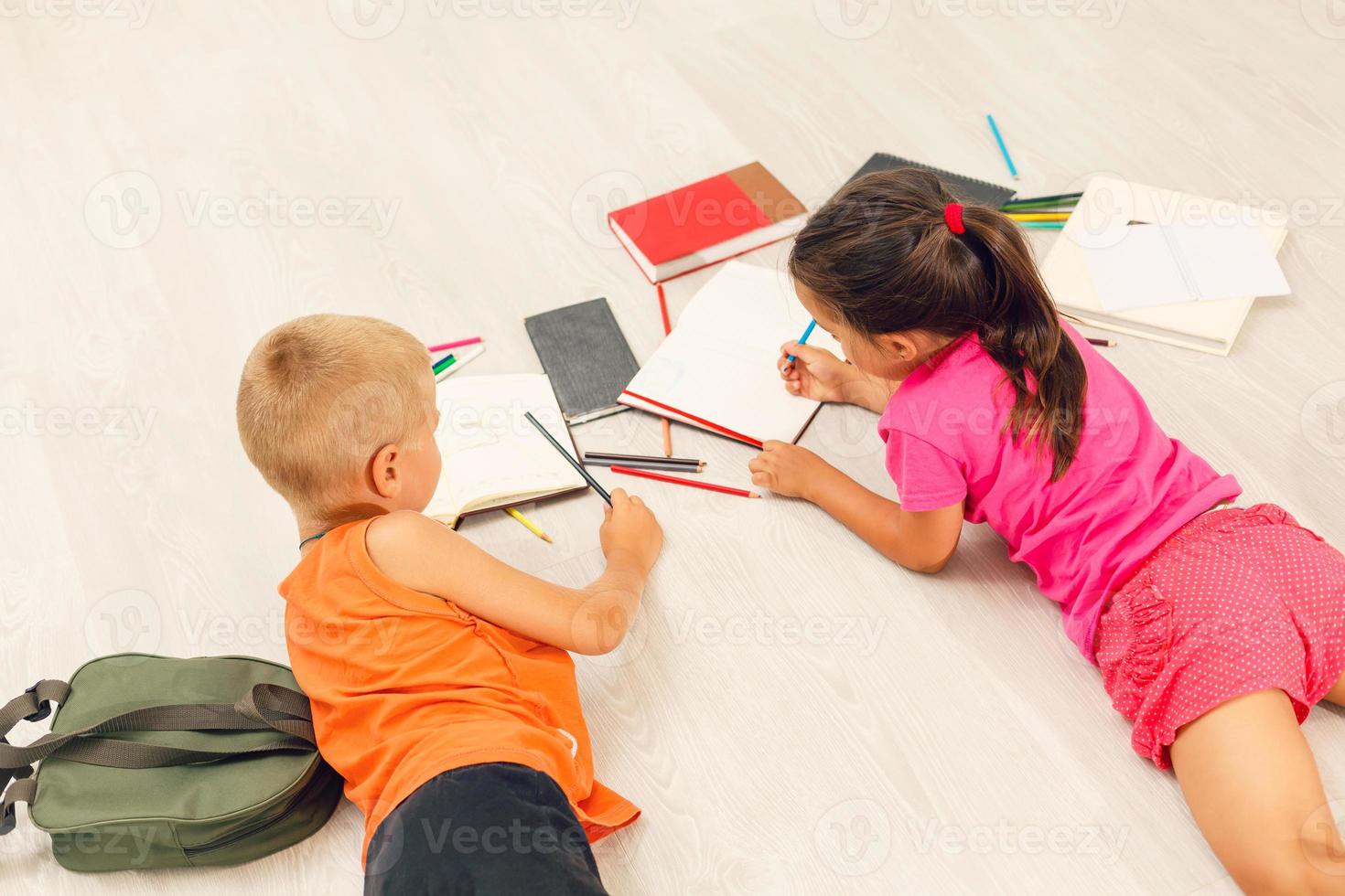 Two cute children draws on floor at home photo