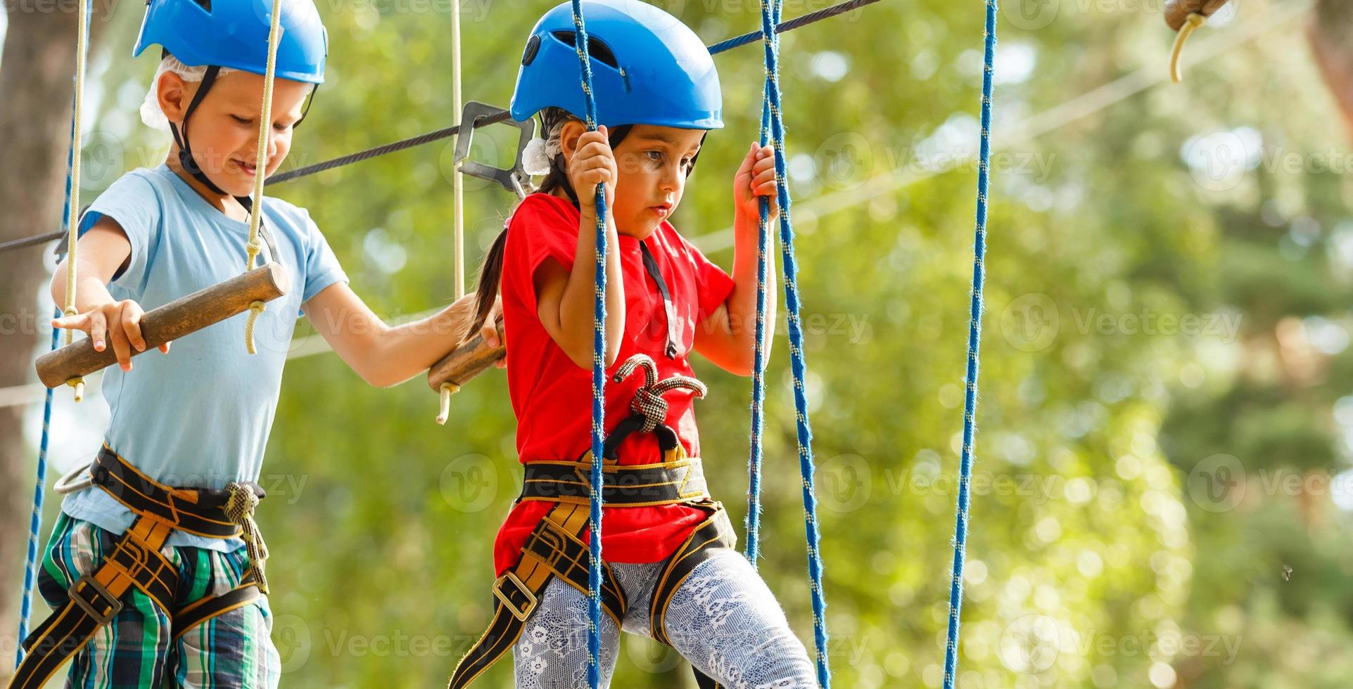 Children - a boy and a girl in the rope park pass obstacles. Brother and sister climb the rope road photo