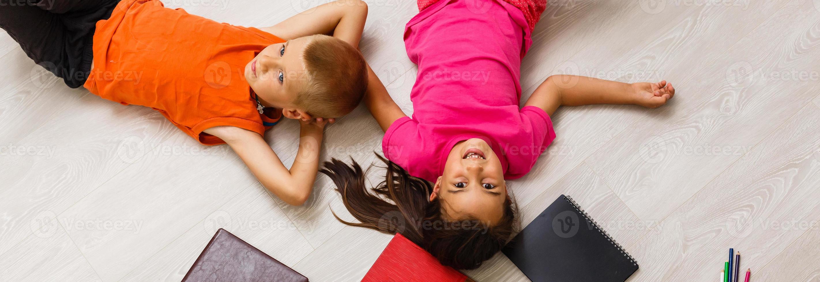 Kids reading for school lying on floor at home photo