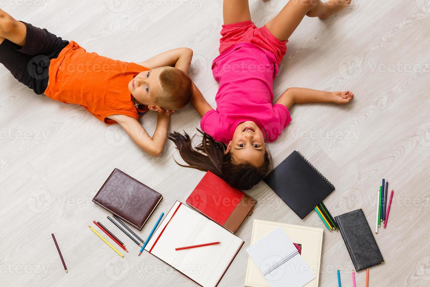 Kids reading for school lying on floor at home photo