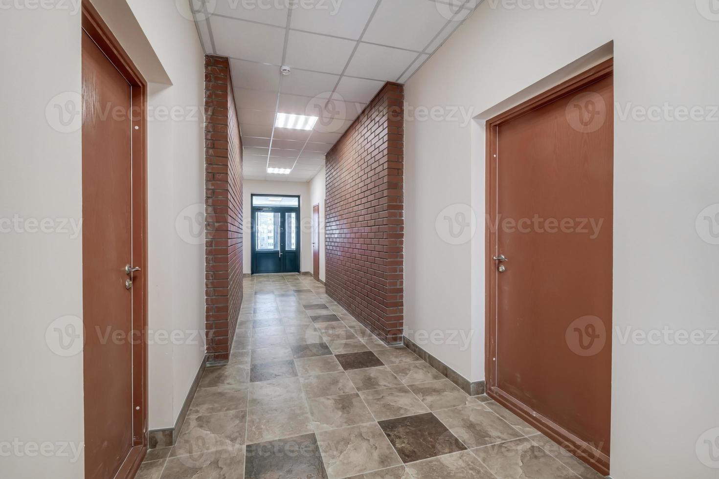 empty long corridor with red brick walls in interior of modern apartments, office or clinic. photo