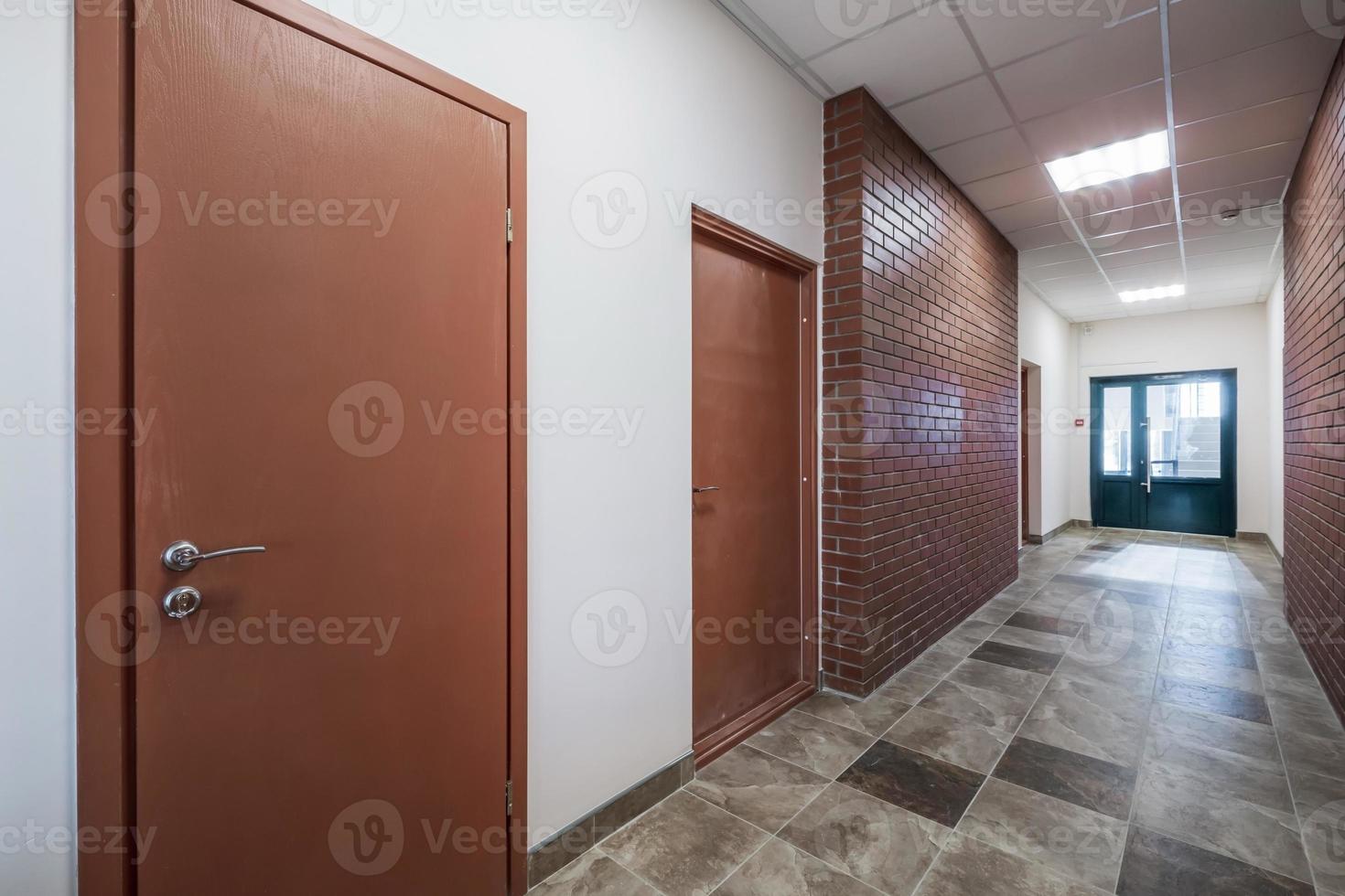 empty long corridor with red brick walls in interior of modern apartments, office or clinic. photo