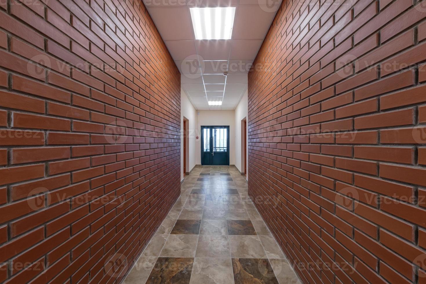 white empty long corridor with red brick walls and doors in interior of modern apartments or office photo