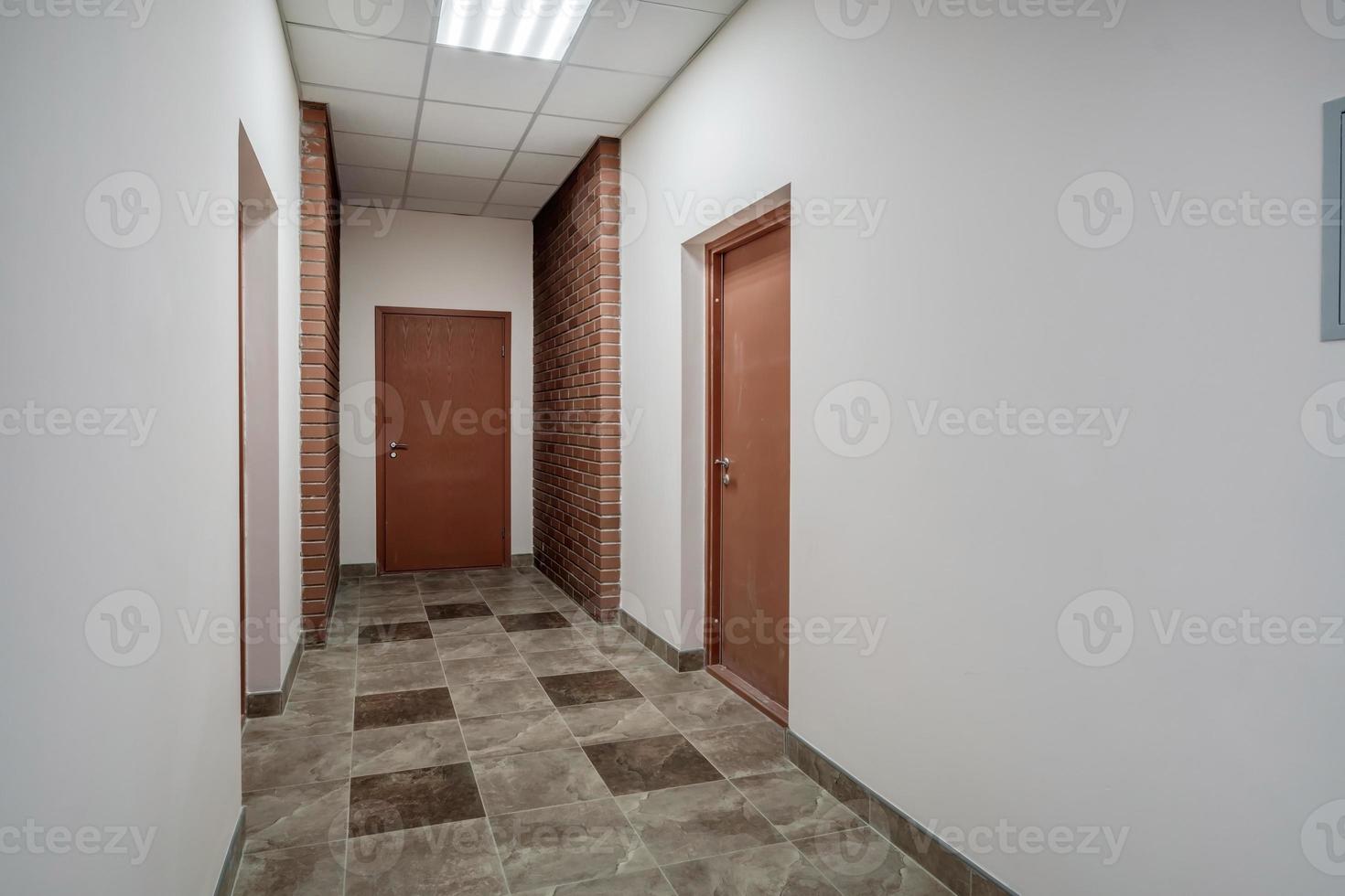 white empty long corridor with red brick walls and doors in interior of modern apartments or office photo