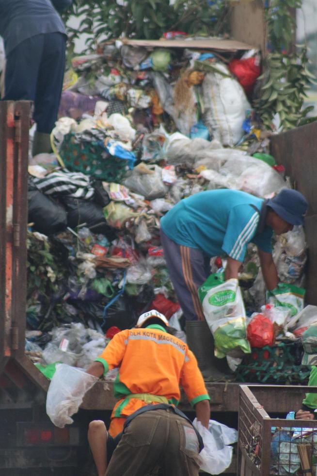 Magelang,Indonesia,2023-Garbage people working together emptying dustbin to dispose of trash with truck loading garbage and dustbin. photo