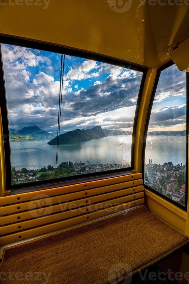 un cable coche fotografiado desde adentro, desde el ventana ver usted ver un lago con montañas foto