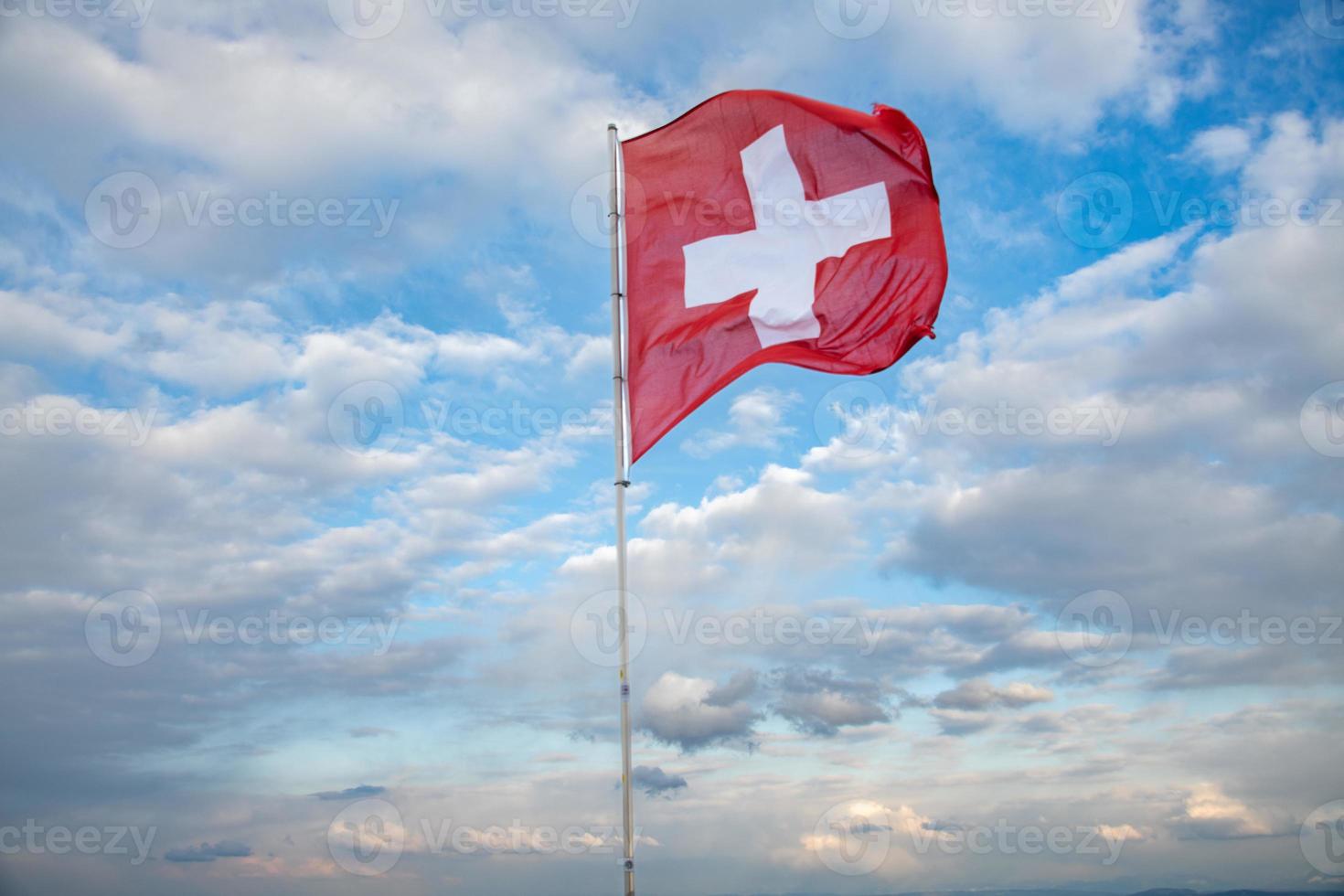 Swiss flag blowing in the wind, the background is a cloudy sky photo