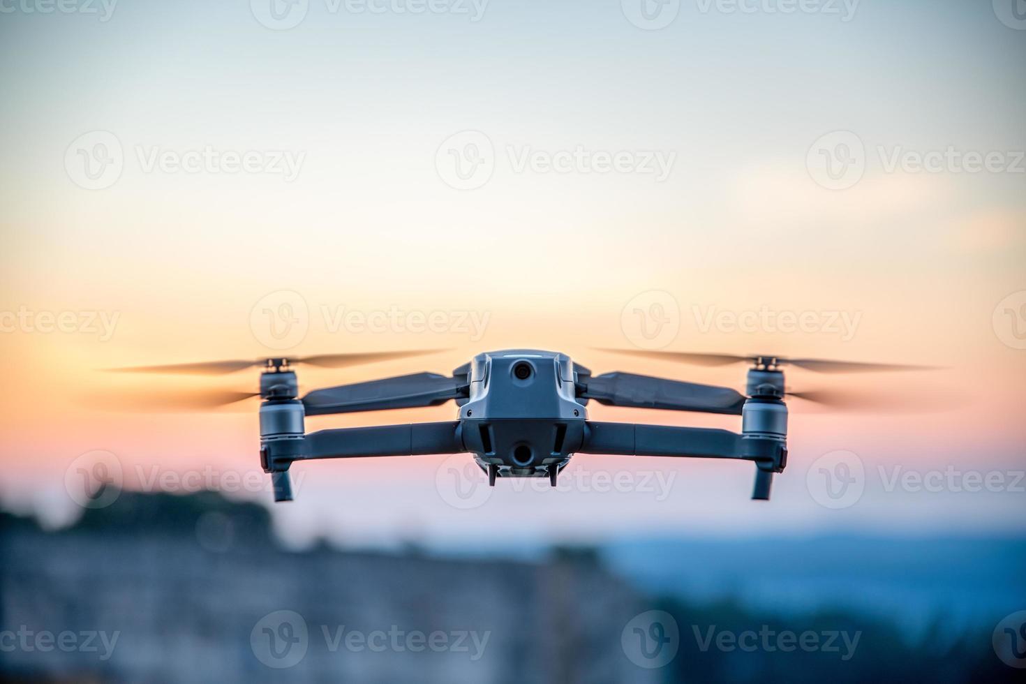 A drone in the air,the background is a purple blurred sky photo