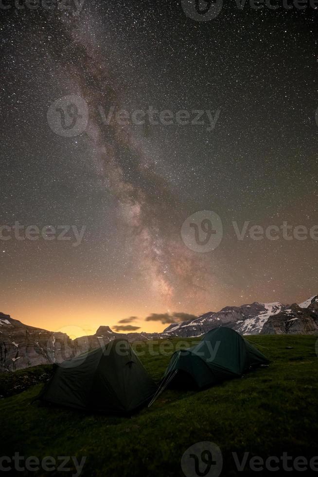 Night shot of the milky way, at a mountain lake,Two tents are in the foreground photo