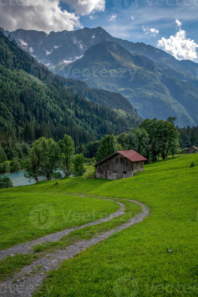 A hut surrounded by mountains in the valley to which a path leads, photo