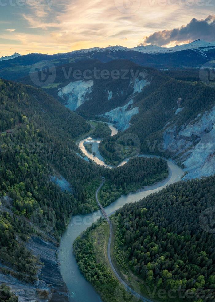 un río ese carreras en un s curva Entre el montañas,hacia puesta de sol foto