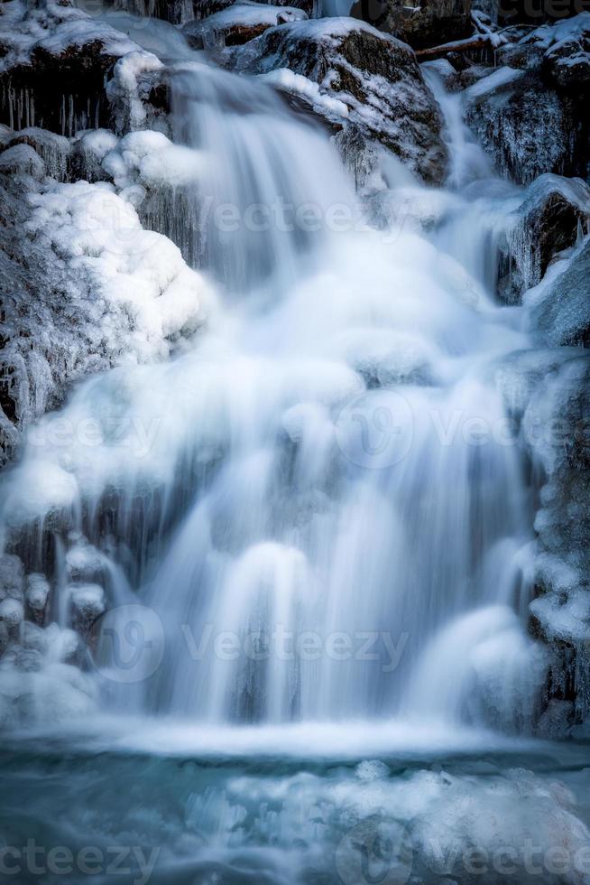 A waterfall in winter surrounded by snow and ice photo