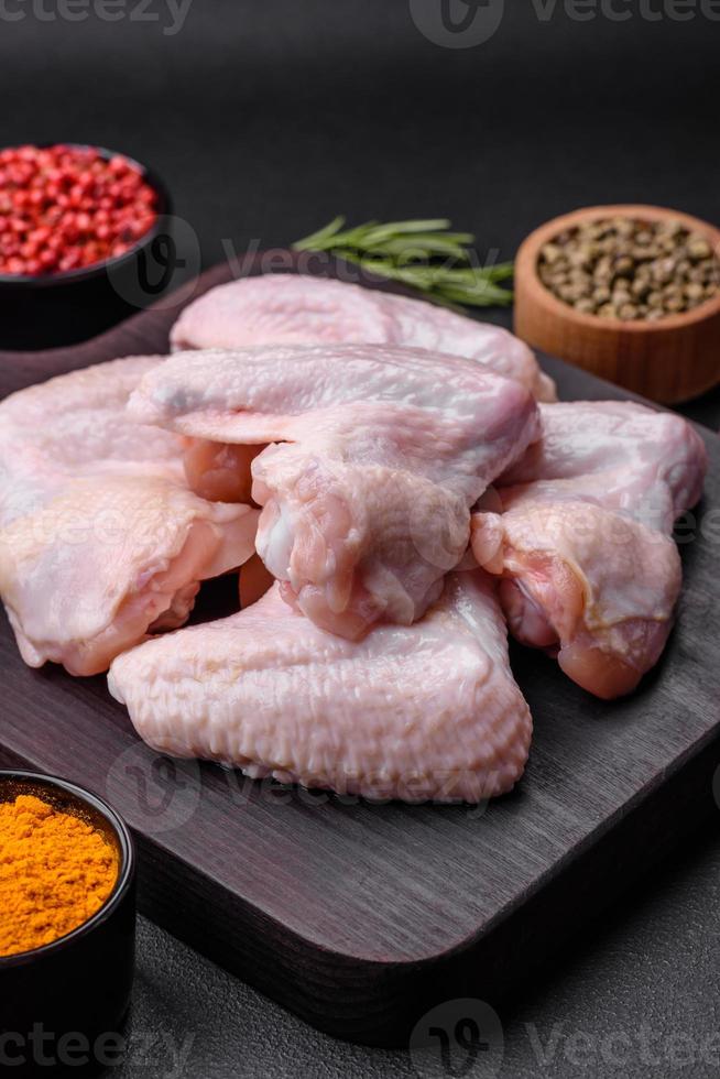 Raw chicken wings with salt, spices and herbs on a wooden cutting board photo