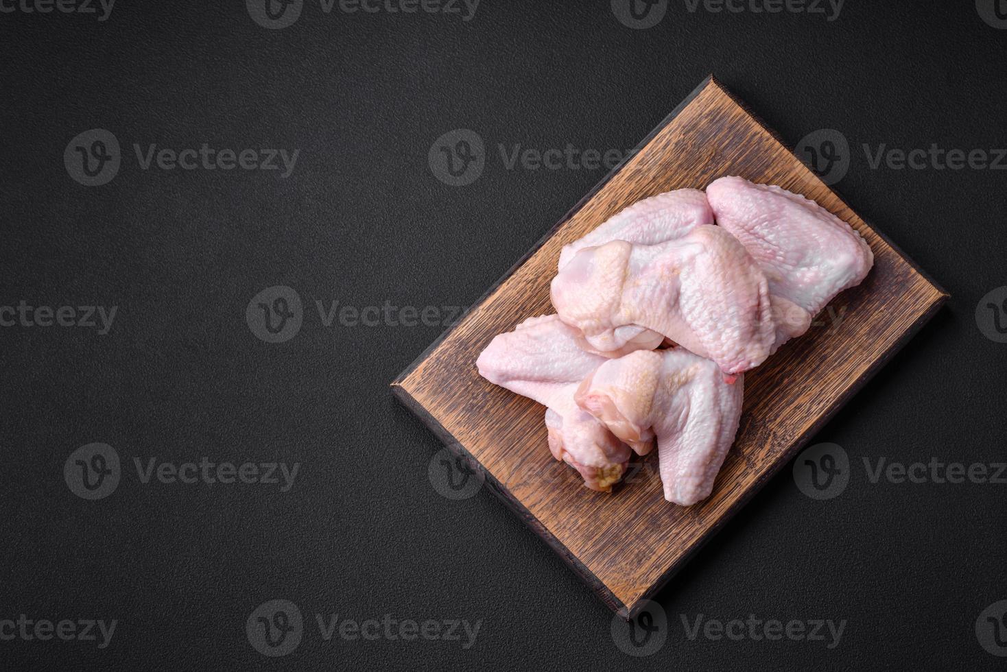 Raw chicken wings with salt, spices and herbs on a wooden cutting board photo